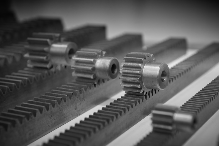 A diagonal view of metal pinion gears on toothed bars with high-precision linear toothed wheels.